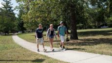 学生 walking down a sidewalk on campus